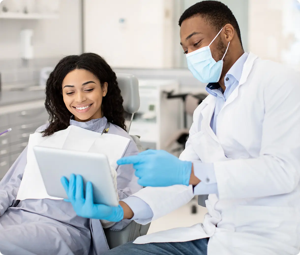 Dentist showing patient information on tablet.