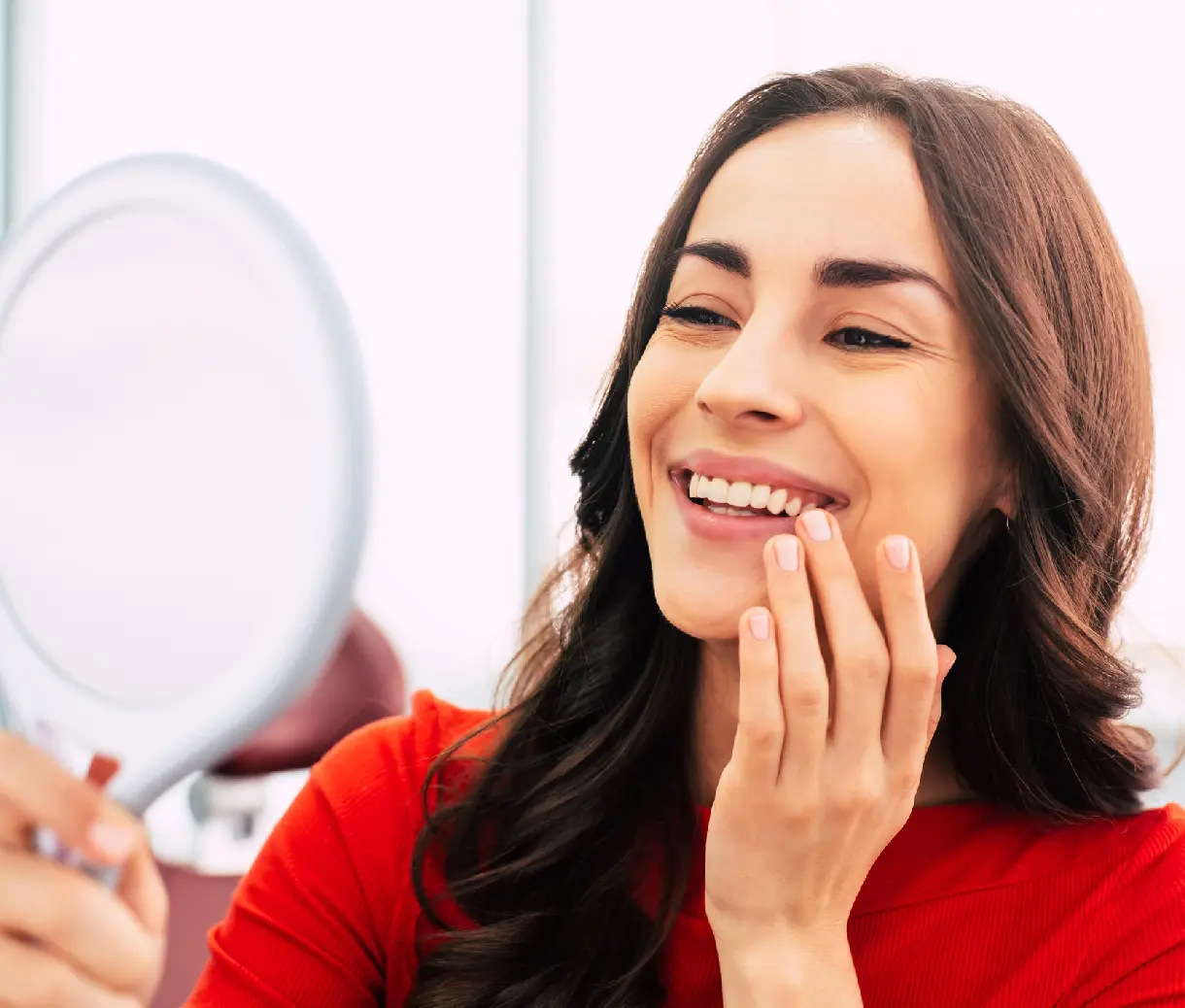 Woman smiling while holding a small mirror.