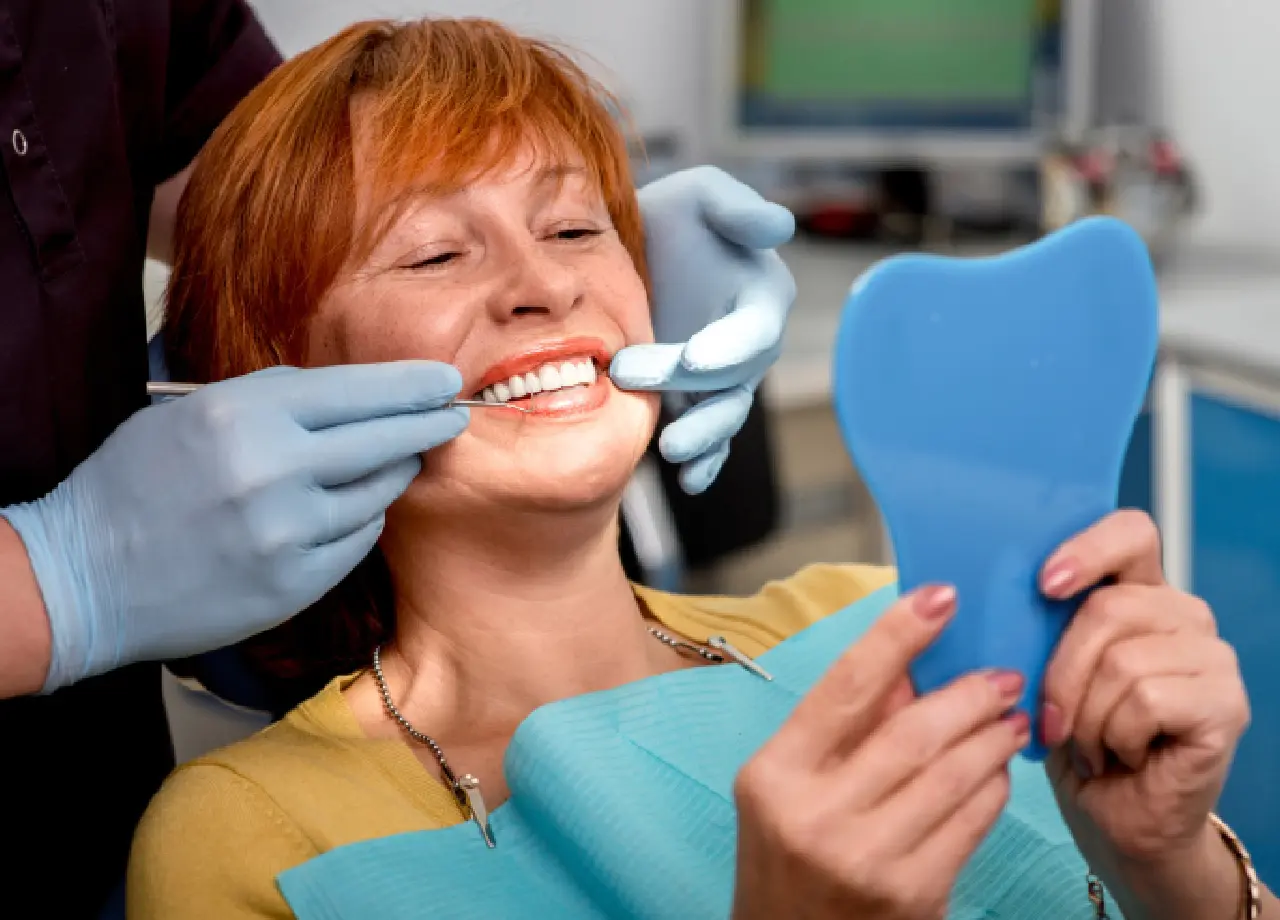 Woman smiling during dental check with mirror.